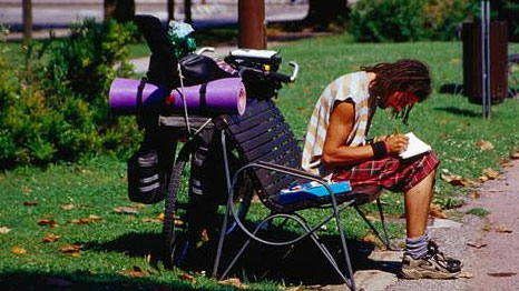 Backpacker sitting on a park bench writing.
