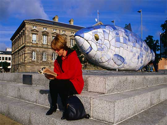  Woman reading in front of 'Big Fish' sculpture on Donegal Quay