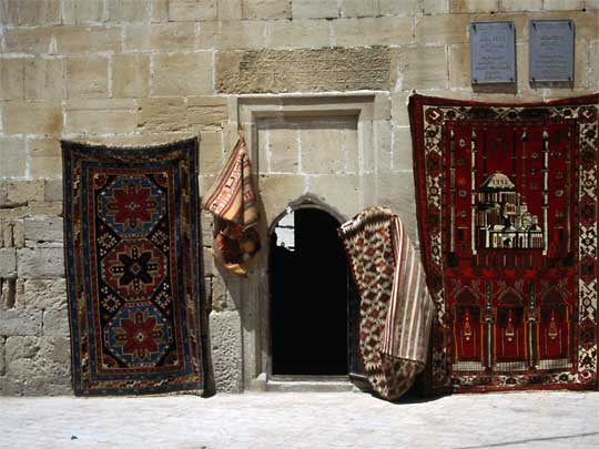  Carpets hang outside entrance to Madrasa Mosque, Old Town, Baku