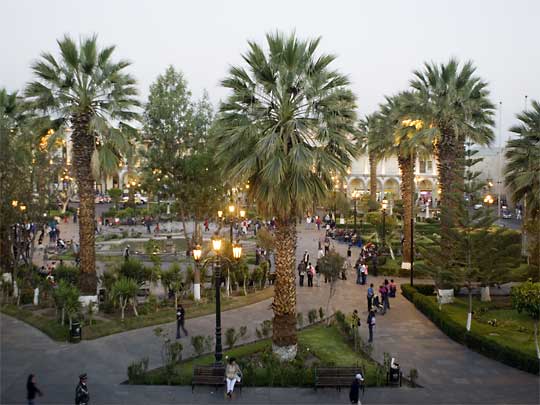  People stroll through palmed Plaza de Armas at dusk