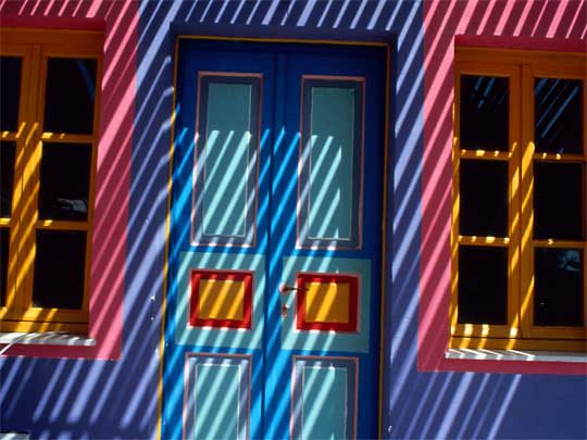  Banded sunlight on pastel painted house, Santorini Island