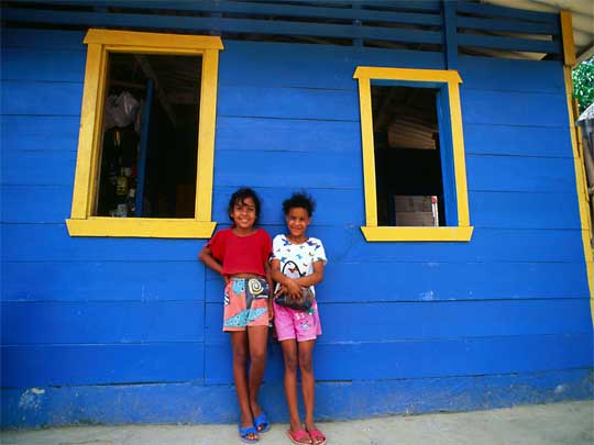 Grinning girls watched over by blue house with yellow eyeshadow