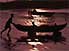 Man pushes dugout canoe to water's edge with two kids on board