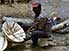 Man sitting on decorated stool, making more decorated stools, near Mamou