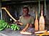 Man selling carvings, bananas and beads in stall near Ponérihouen