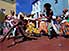Group of colourfully clad dancers give a Capoeira performance in the street